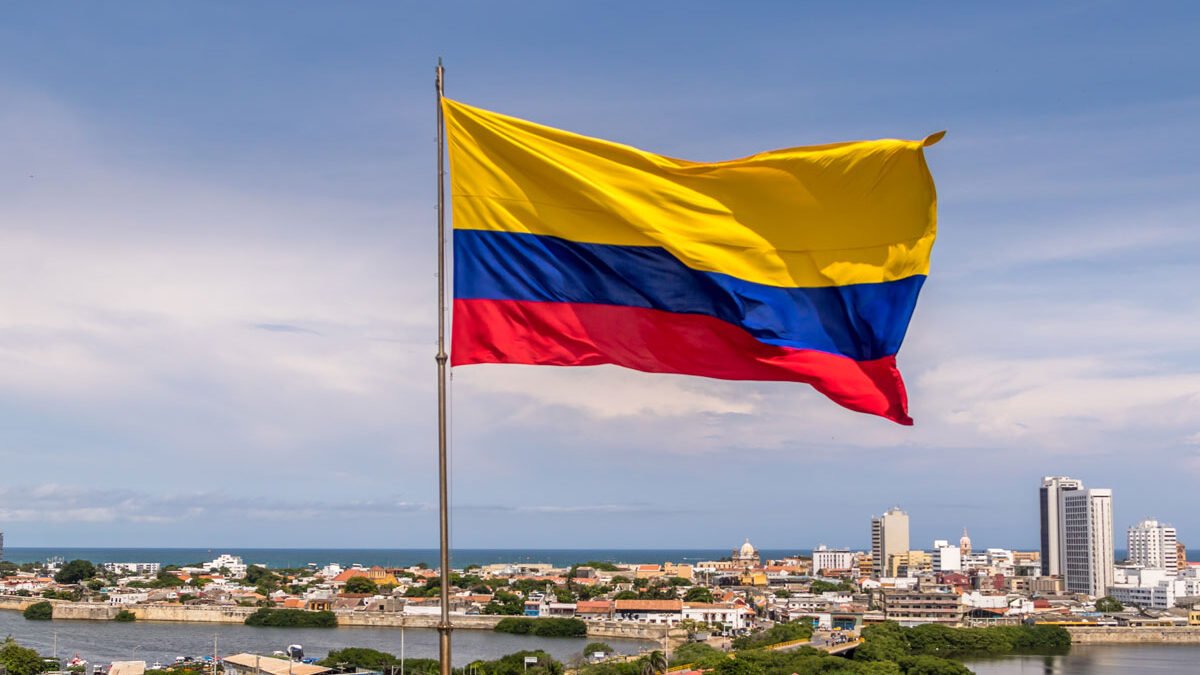 Bandera de colombia ondeando sobre vista panoramica de cartagena de indias, se puede ver el mar en el fondo.