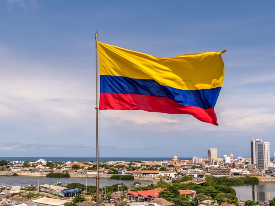 Bandera de colombia ondeando sobre vista panoramica de cartagena de indias, se puede ver el mar en el fondo.