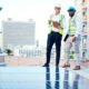 Ingenieros de pie en techo de edificio revisando una instalación de paneles solares.