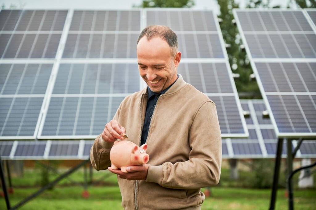 Hombre joven invirtiendo y ahorrando frente a unos paneles solares