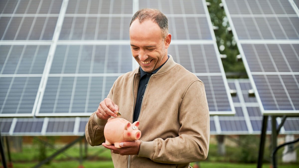 Hombre joven invirtiendo y ahorrando frente a unos paneles solares