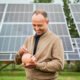 Hombre joven invirtiendo y ahorrando frente a unos paneles solares