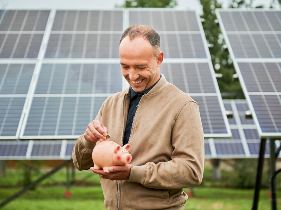 Hombre joven invirtiendo y ahorrando frente a unos paneles solares