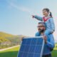 Un padre con su hija sobre sus hombros mirando hacia el futuro, sostiene en la mano un panel solar y en el fondo se ve un campo verde y cielo azul